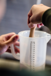 A Person Holding White Plastic Measuring Cup