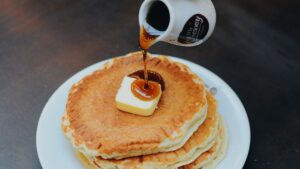 Person Pouring Syrup on Pancake