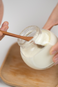 Crop man taking natural yogurt with spoon from jar